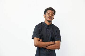 Confident black man in a stylish black shirt, standing with arms crossed against a neutral background, showcasing a relaxed and self-assured demeanor.