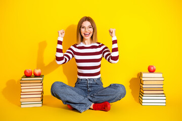 Charming young woman in casual striped outfit excitedly gestures while sitting on floor surrounded...