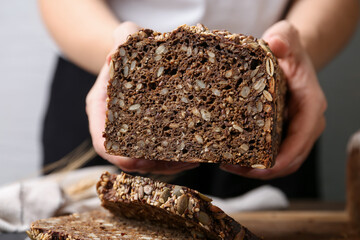 Woman with freshly baked bread at table against grey background, closeup