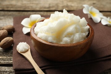 Natural shea butter and plumeria flowers on wooden table, closeup