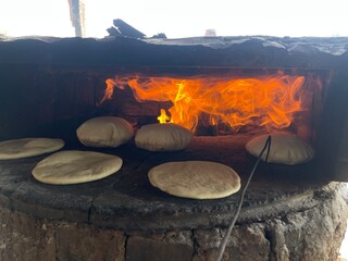 Baking bread on a clay oven, traditional firewood baking method.