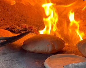 Baking bread on a clay oven with firewood.