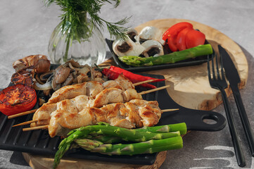 Barbecue on bamboo sticks. Grilled chicken kebab with mushrooms, asparagus and tomato. Red hot kebab.