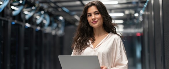 The woman confidently holding a laptop in a modern data center.