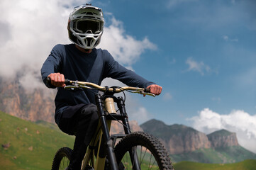 Athlete rider in bicycle helmet on his bike standing and resting before descent in mountains...
