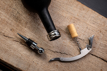 Wine accessory kit, containing a corkscrew, a ring and a wine bottle cap, seen from above on rustic...