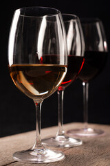 Crystal glasses with red and white wine
over rustic wooden table on black background