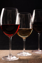 Crystal glasses with red and white wine
over rustic wooden table on black background