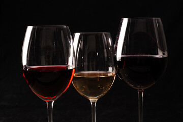 Crystal glasses with red and white wine
over rustic wooden table on black background