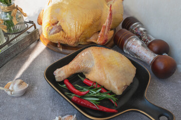 Raw chicken leg. A piece of fresh raw chicken leg with red chilli. displayed on a black stylish ceramic baking pan