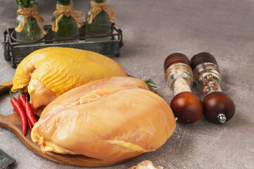 Chicken breasts with and without skin. Raw chicken breast fillets with rosemary and spices on a wooden cutting board