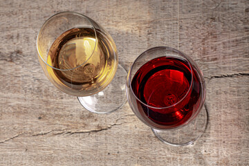 Crystal glasses with red and white wine
over rustic wooden table on black background