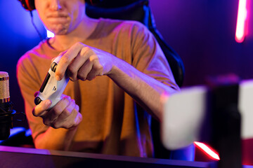 Enjoy smart gaming streamer with control joystick, playing game online of live streaming by smartphone rec with team skilled players on computer at modern technology cyber neon light room. Pecuniary.