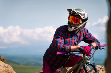 Athlete rider in bicycle helmet on his bike standing and resting before descent in mountains...