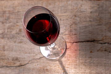
Crystal goblet with red wine on the rustic wooden table on black background.