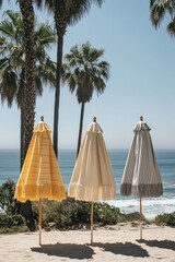 Umbrellas stand on a sandy beach with palm trees and ocean waves under a clear blue sky during daylight