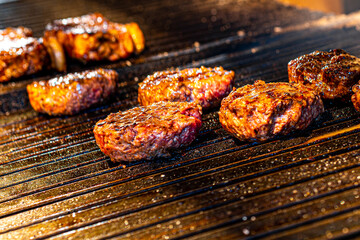 Various burgers being grilled over hot coals