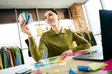 Professional designer in modern atelier reviewing color palette for fashion concept creation in collaborative workspace