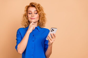 Young businesswoman in a blue shirt contemplating a decision while engaging with her smartphone on...