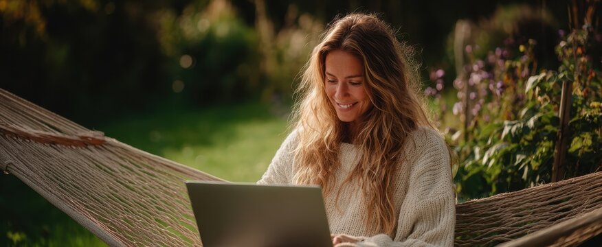 The woman enjoying a peaceful moment in a hammock while working on her laptop. - Powered by Adobe