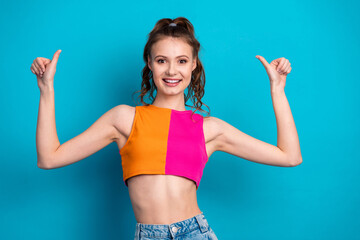 Smiling young woman in colorful crop top posing confidently against a vivid blue background,...