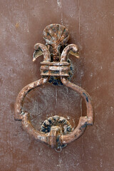 Vintage wrought iron door knocker on old wooden door