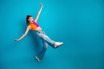 Naklejka premium Energetic young woman posing playfully in colorful casual attire against bright blue background