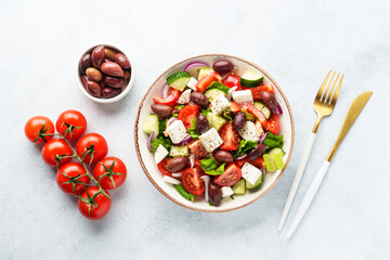Greek salad with olives on white table. Fresh vegetables, cheese and olive oil. Top view with space for design.