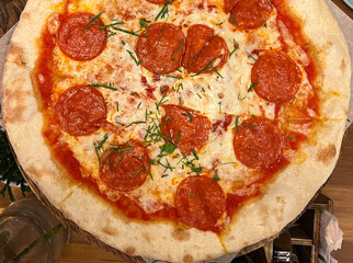 Italian pizza with whole pieces of sausage on table background.