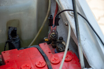 Mechanic inspects battery connections and wiring in a vehicle engine compartment, ensuring proper...