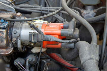 A mechanic examines the ignition system components of a classic truck inside a garage during...