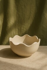 A beautiful, elegantly designed, off-white ceramic bowl sits gracefully. The bowl has a lovely wave-like rim