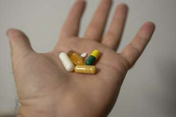 Open hand displaying variety of colorful pills and capsules in medical health concept