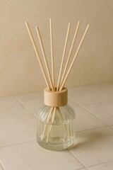 Aromatherapy reed diffuser set in a clear glass bottle on a tile surface, diffusing fragrance in home