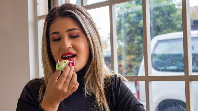 Young woman eating a delicious oblea in front of window