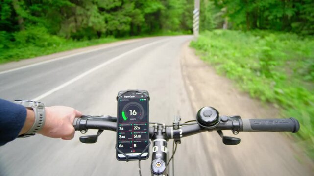 A cyclist pedals through a lush landscape, smartphone mounted on handlebars to track speed and performance