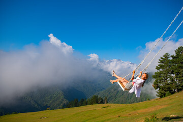 Girl swinging on a swing in the mountains of Georgia in Ushguli