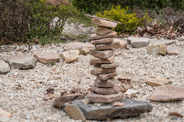 Natural stone tower or cairn in a rocky, vegetated outdoor setting Rectangular, textured stones...