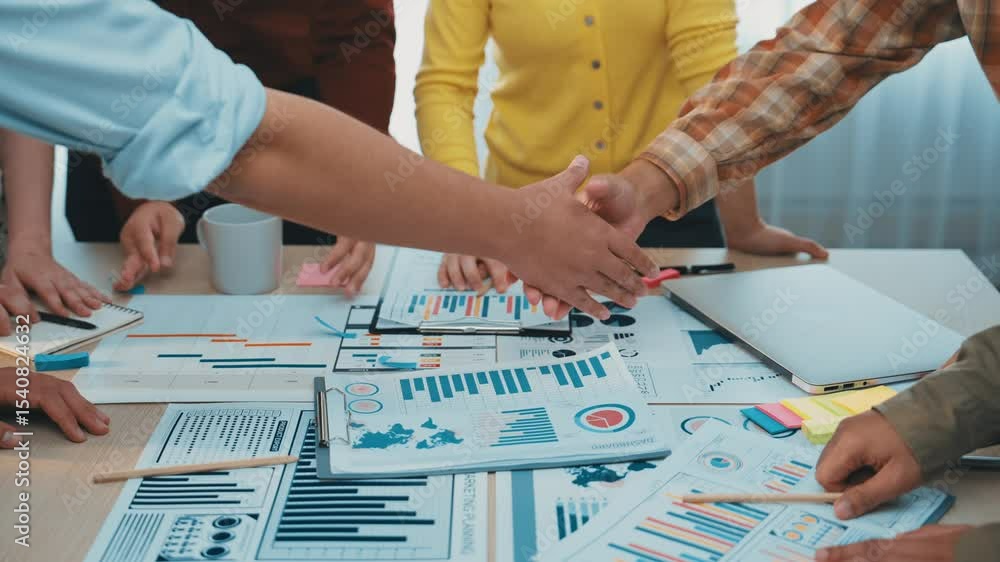 Poster a dynamic team collaborates on business strategies, examining graphs and charts spread across a tabl