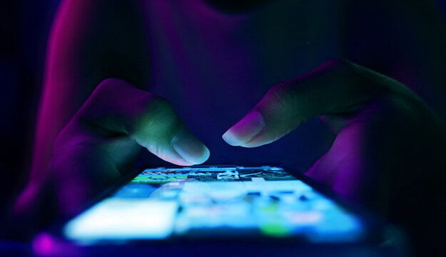 Finger of woman touching scroll page app on mobile phone.In a room with blue and purple neon tones.concept Social media and marketing