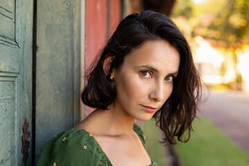Portrait of beautiful young woman with short hair and green eyes in front of old house