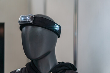 Headless mannequin with jacket, headlamp accessory in indoor setting storeexhibition area, bluish...