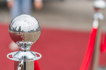 Indoor scene with red carpet leading to a silver trophy stand Large metallic trophy with reflective...