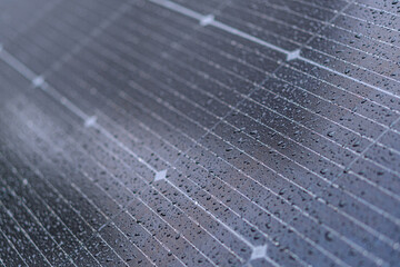 Close-up view of a solar panel with photovoltaic cells, water droplets, natural lighting, top-down...