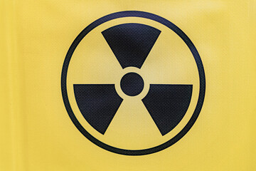 Yellow radiation symbol on fabric, possibly clothing. three radiating lines emanating from a...