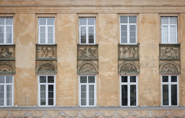 Many old windows with white frames and relief inserts on the wall. Neoclassical building, facade of...