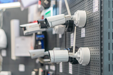 Wall-mounted collection of security cameras in an industrial setting, arranged on a metal plate Indoor lighting with no shadows No text visible