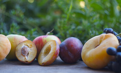 Plums cut in two and other fruits behind them