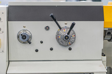 A white industrial control panel with three circular dials, partially obscured equipment, and an...
