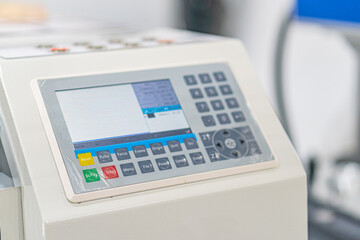 Off-center image of an industrial machine with a digital control panel The control panel is white...